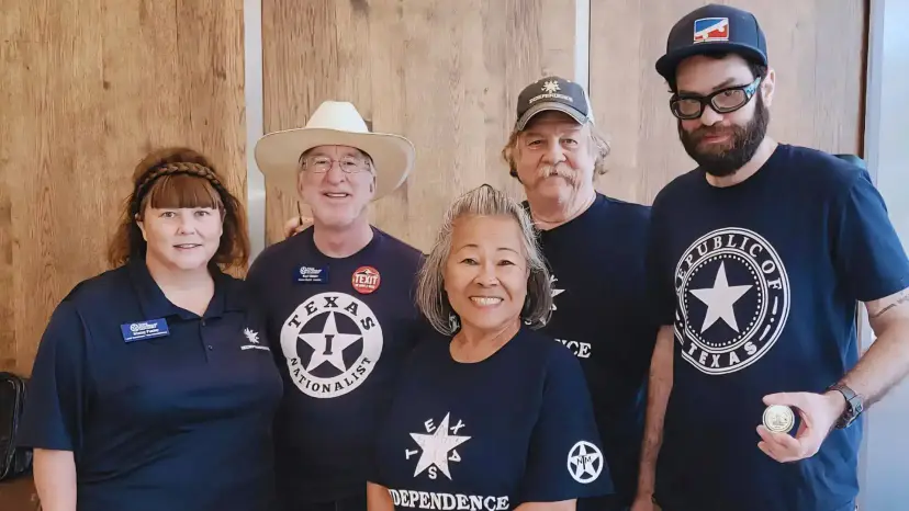 Five TNM members in shirts reading 'Texas Nationalist' and 'Republic of Texas' pose together indoors, one holding a coin.