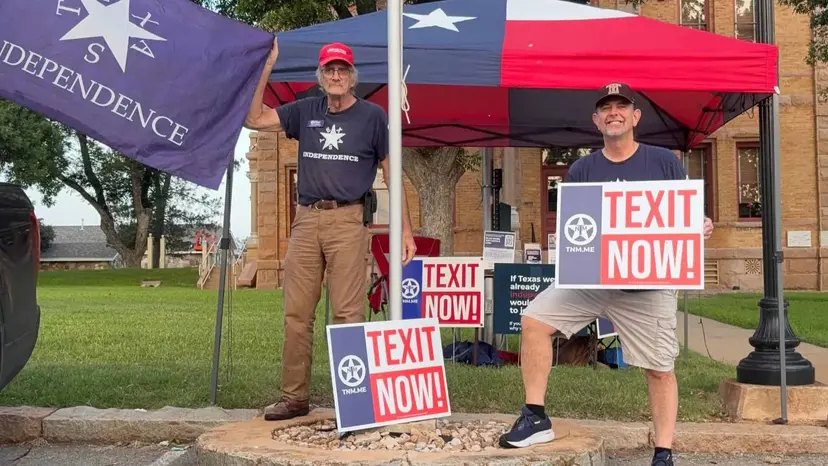 Two volunteers with 'TEXIT Now!' signs and a Texas Independence flag outside the Llano County courthouse.