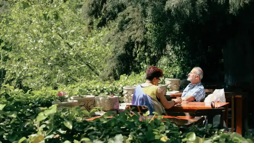 A retired couple at an outdoor table in a garden