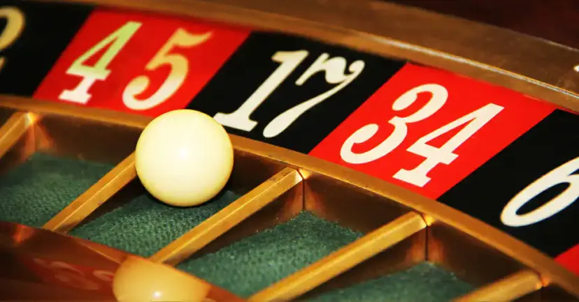 Close view of a white ball resting in a pocket of a roulette wheel beside red and black numbers.