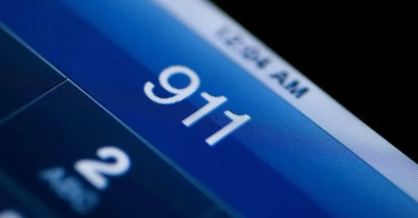 Close-up of a blue phone screen showing the numbers 911 being dialed.