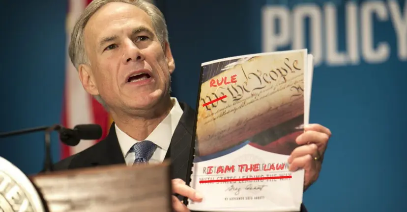 Texas Governor Greg Abbott speaking at a podium, holding up a booklet with "We the People" marked up in red.