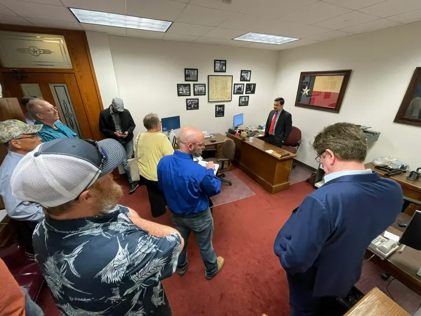 Supporters stand in a legislator's Capitol office speaking with a staff member in a suit.