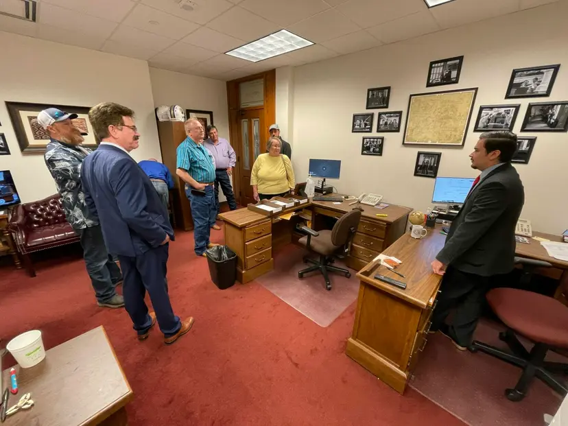 A small group of visitors talks with a man in a dark suit inside a Capitol office.