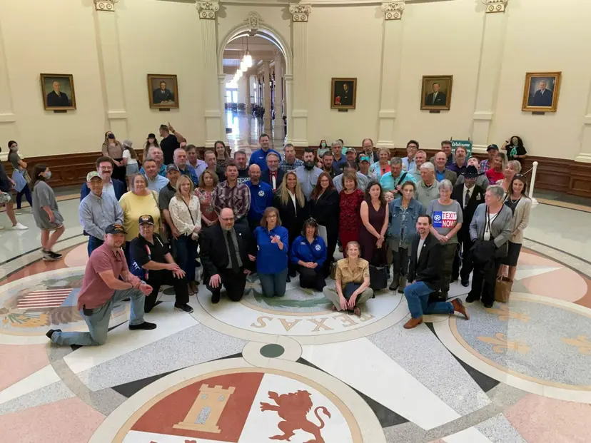 Supporters pose for a wide group photo on the terrazzo seal floor of the Texas Capitol rotunda.