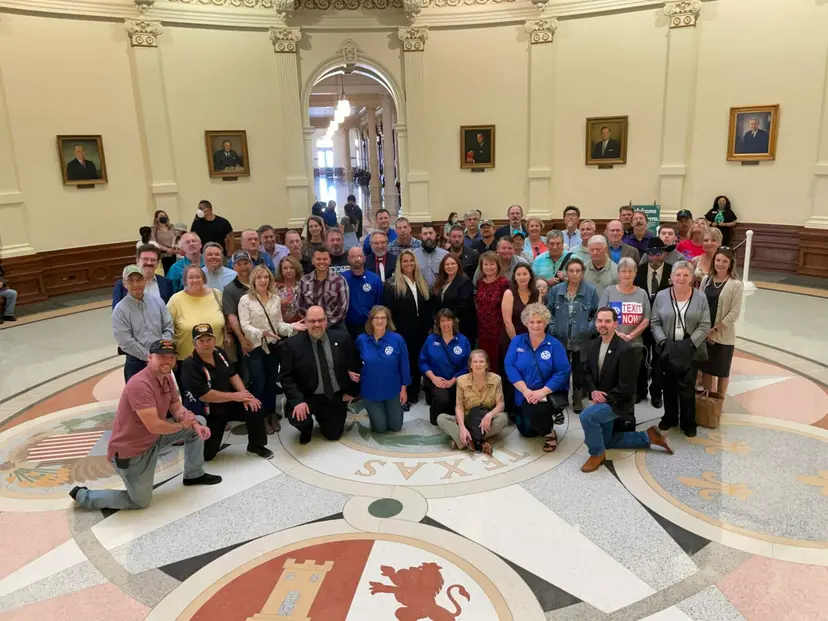 A crowd of TEXIT supporters kneels and stands for a group photo in the Capitol rotunda.