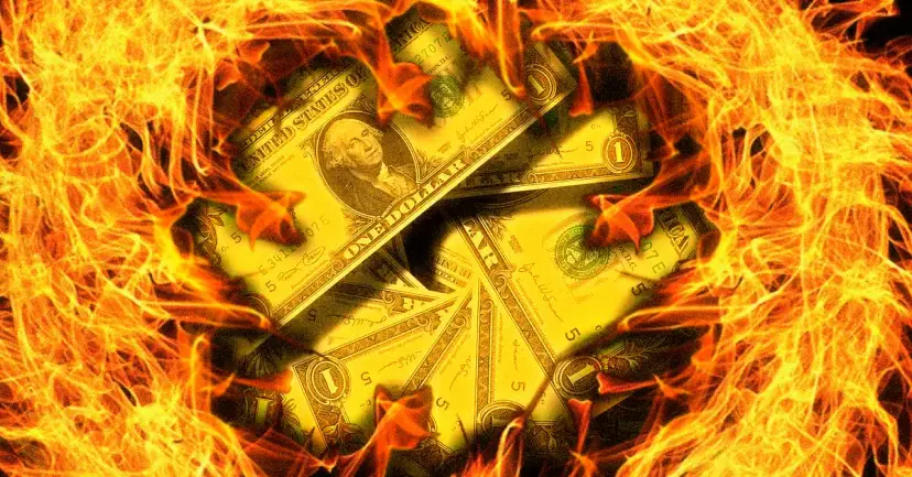 U.S. dollar bills engulfed in bright orange flames.