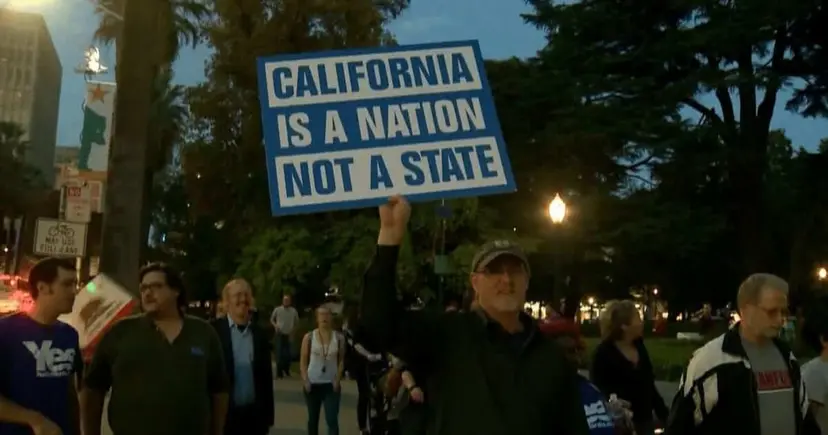 Demonstrators at a nighttime rally, one man holding up a sign reading 'California Is a Nation, Not a State.'
