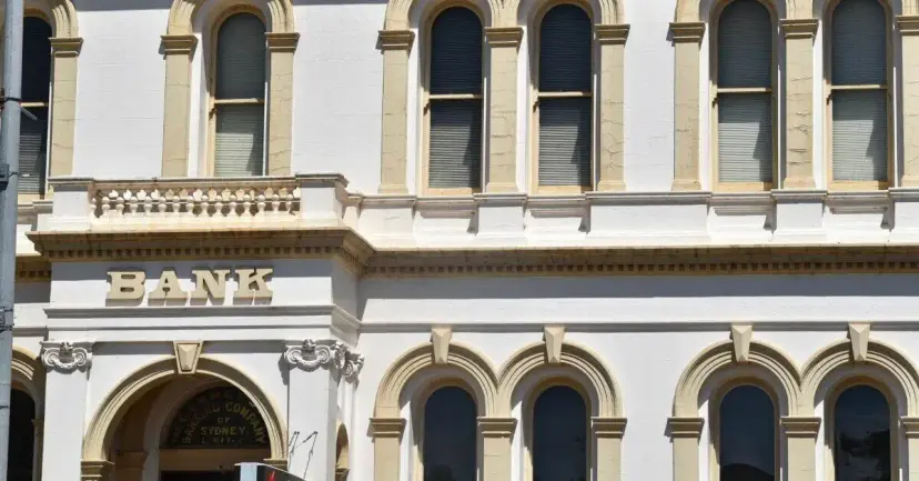 A white historic building with arched windows and the word 'Bank' above the entrance.