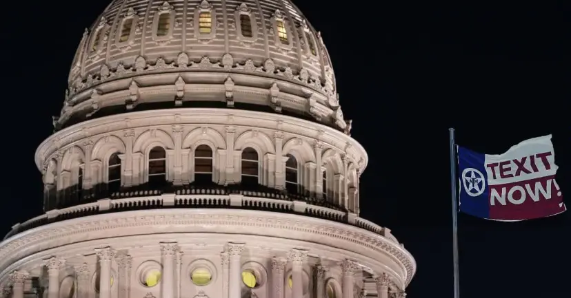 The Texas Capitol dome at night with a 'TEXIT Now!' flag flying beside it.