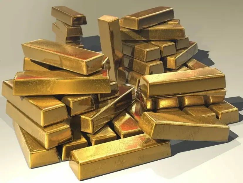 Pile of shiny gold bars stacked on a light background.
