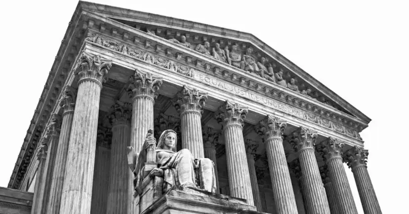 Low-angle black-and-white view of the federal Supreme Court building's columns and a seated marble statue.