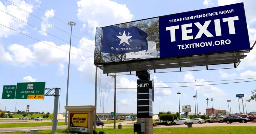 Highway billboard with a blue Independence flag and the words 'Texas Independence Now! TEXIT, texitnow.org' under a cloudy sky.