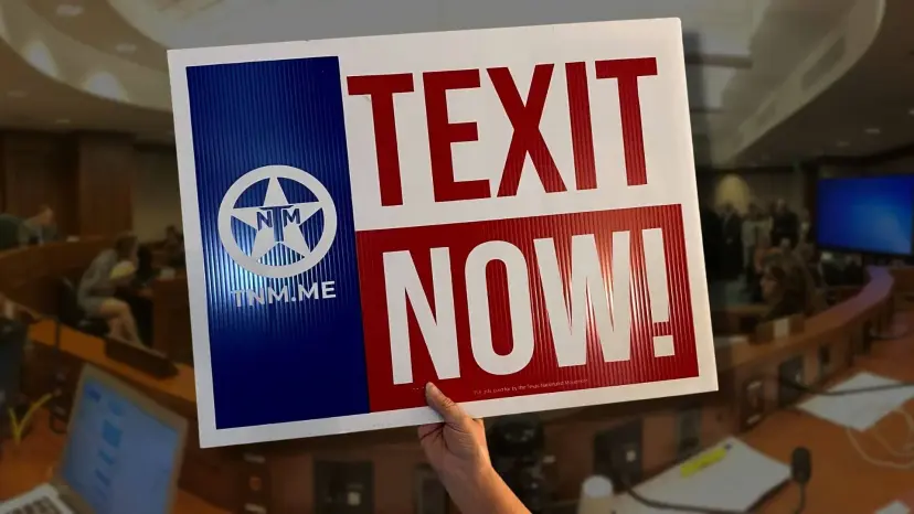 Hand holding a TEXIT NOW sign inside a Texas House committee hearing room
