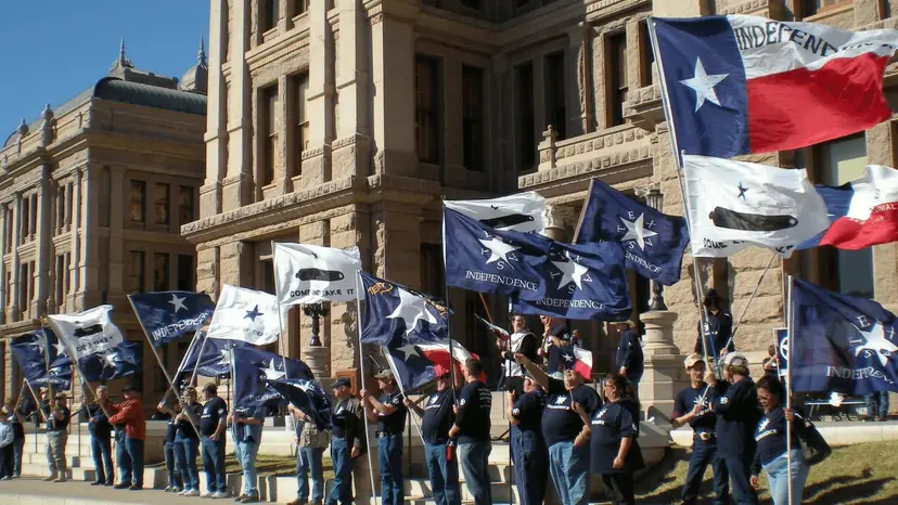 Supporters in navy shirts holding Texas flags and blue independence flags outside the Texas State Capitol.