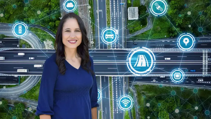 Terri Hall in a navy dress stands over an aerial view of highway interchanges with network icons.