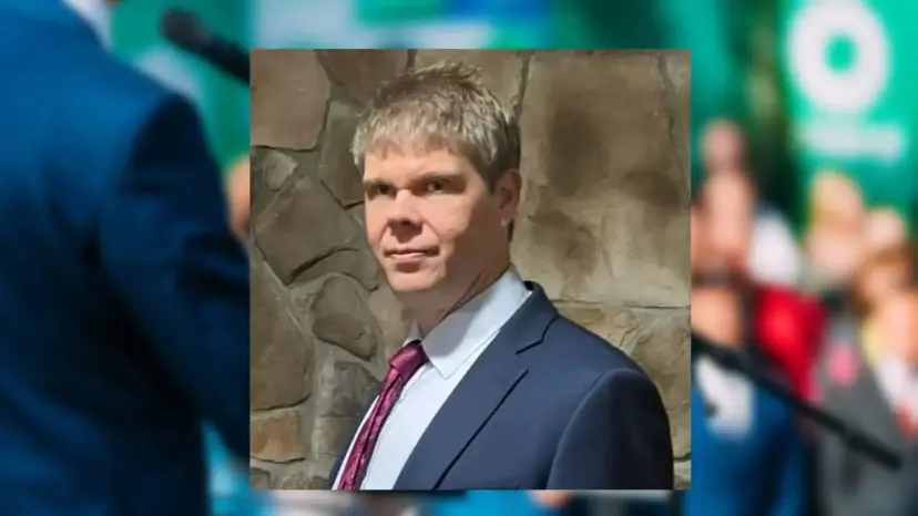 Portrait of Aaron R. Day in a suit and red tie in front of a stone wall.