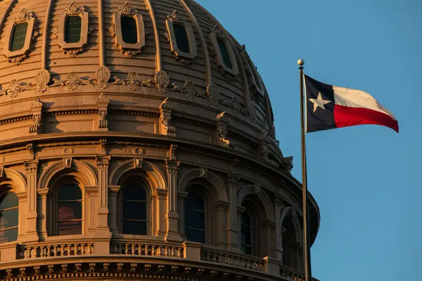 The Texas Capitol dome in warm evening light, with a Texas flag flying beside it.