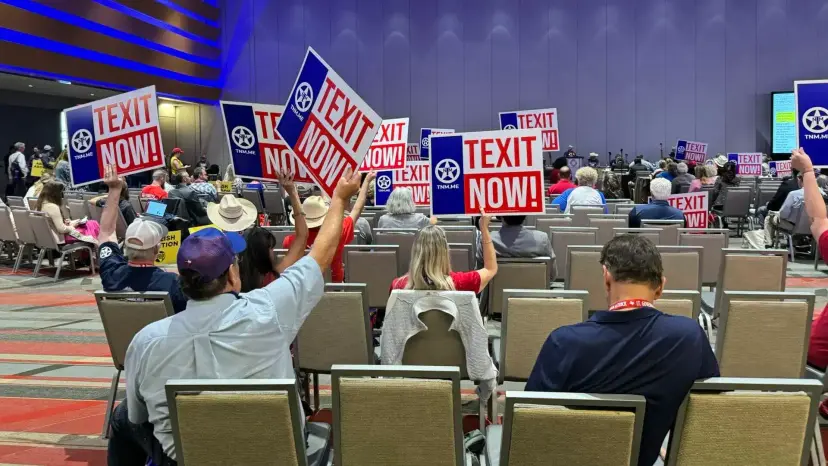 Convention delegates seated in a large hall hold up red, white and blue 'TEXIT Now!' signs.