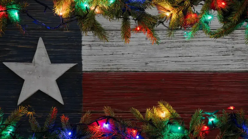 Rustic wooden Texas flag framed by pine branches and strings of colorful Christmas lights.