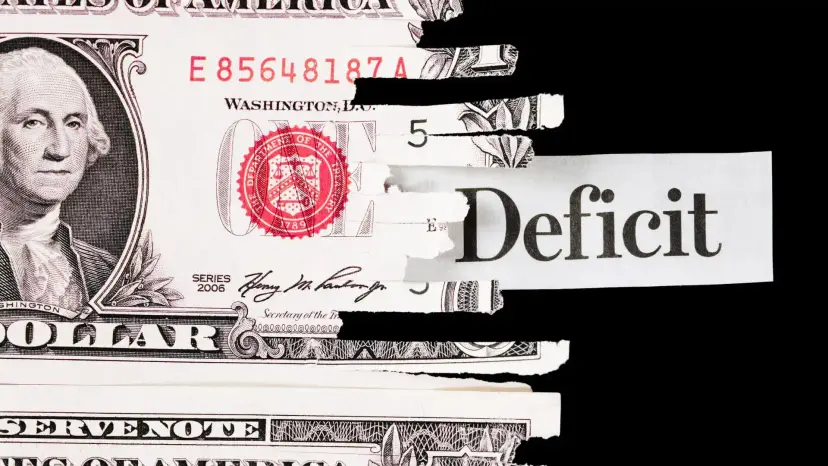 Torn dollar bill revealing a newspaper clipping that reads 'Deficit' against a black background.