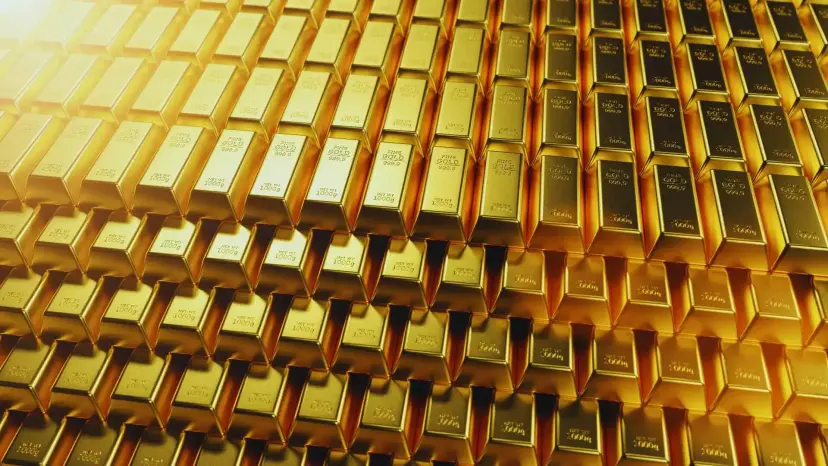 Rows of stacked gold bars glowing under warm light.