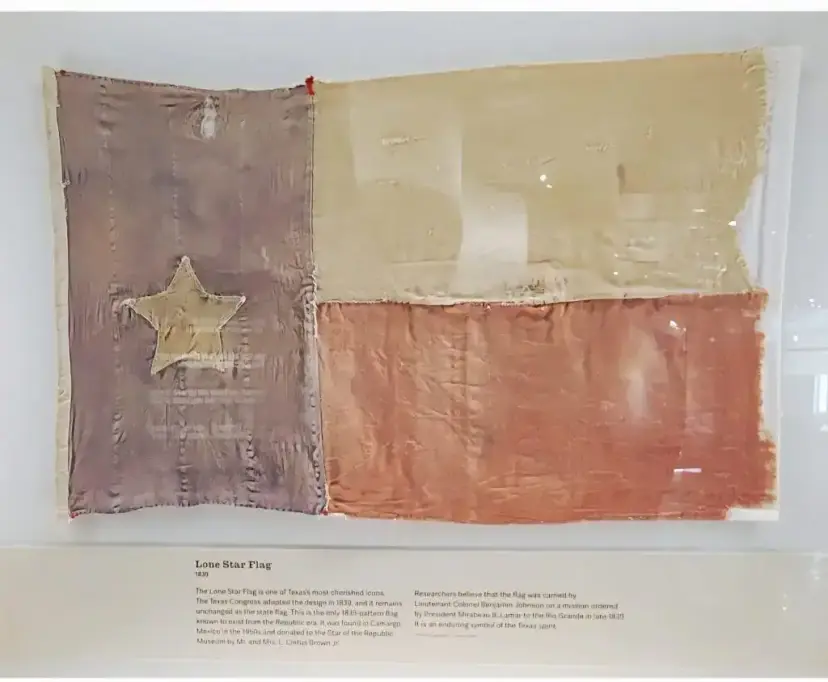 The faded 1839 Lone Star Flag displayed in a museum case above an interpretive label.