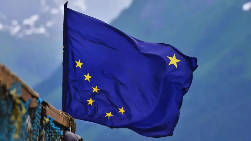The blue Alaska state flag with its eight gold stars, flying in front of mountains.