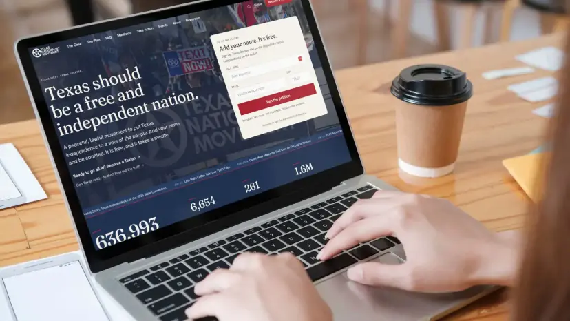 A person typing on a laptop showing a Texas Nationalist Movement web page and petition sign-up form.