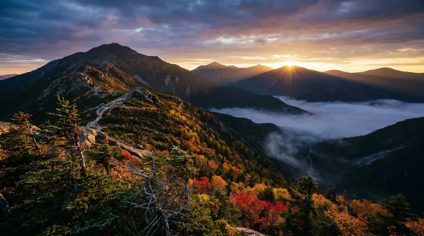 The White Mountains of New Hampshire at dawn, rugged granite peaks and autumn foliage under a dramatic sky