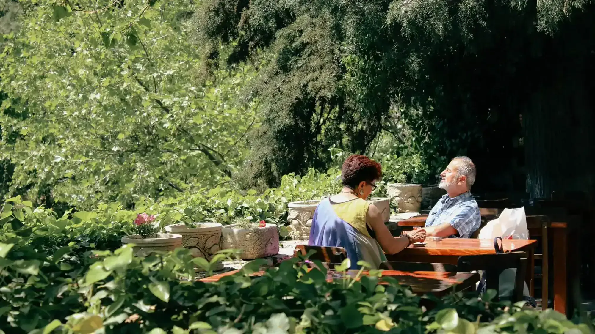 A retired couple at an outdoor table in a garden