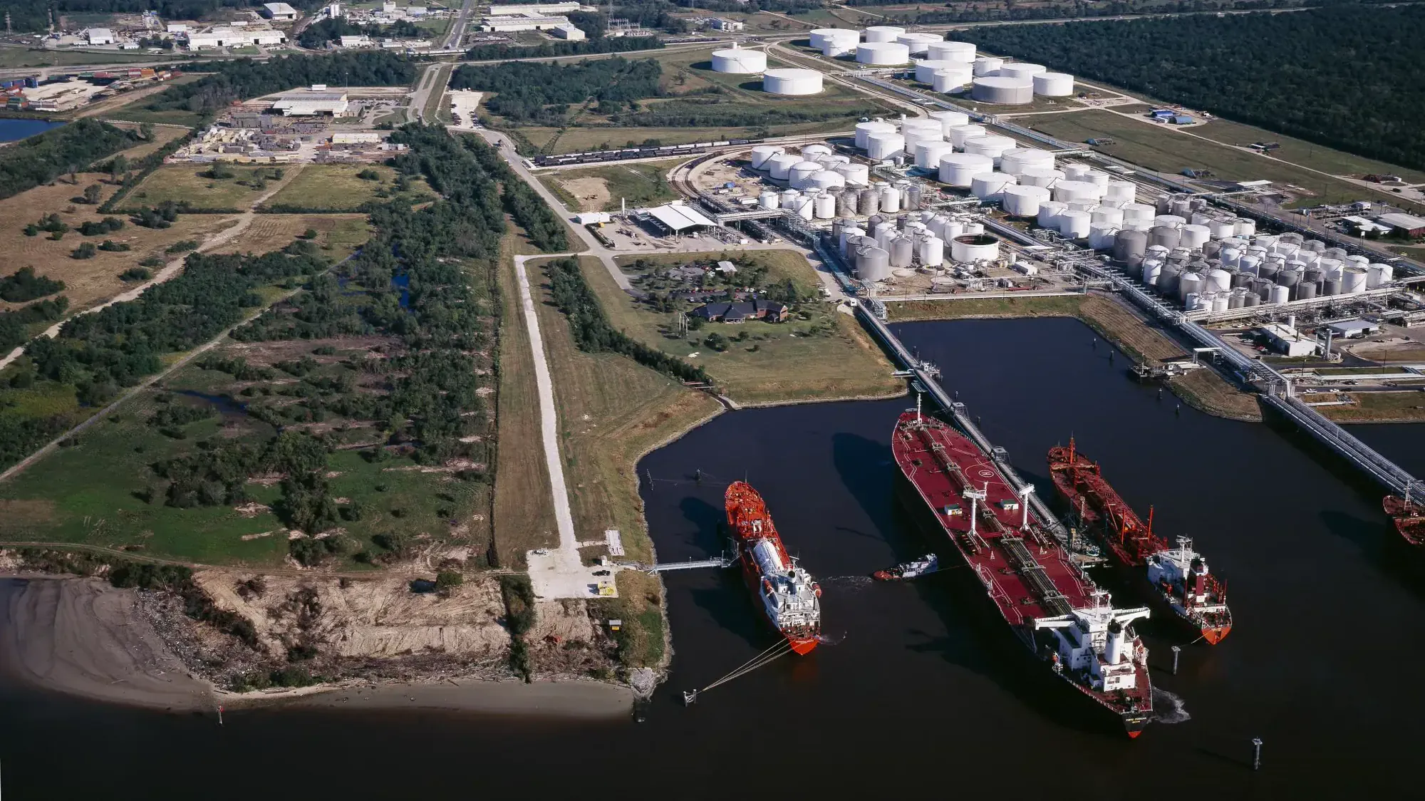 Tankers docked along the Houston Ship Channel beside storage tanks