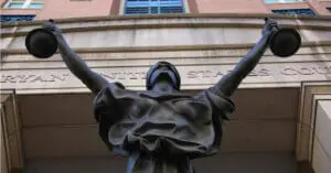 A bronze statue of blindfolded Lady Justice holding up scales outside a federal courthouse