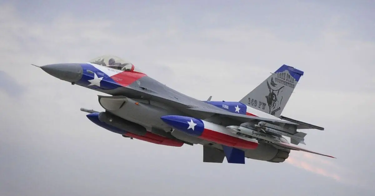 An F-16 fighter jet painted in Texas flag colors in flight against a cloudy sky.