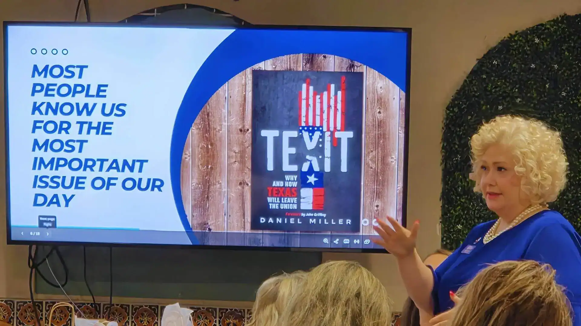 A woman presenting to an audience beside a screen showing the cover of Daniel Miller's book 'TEXIT.'