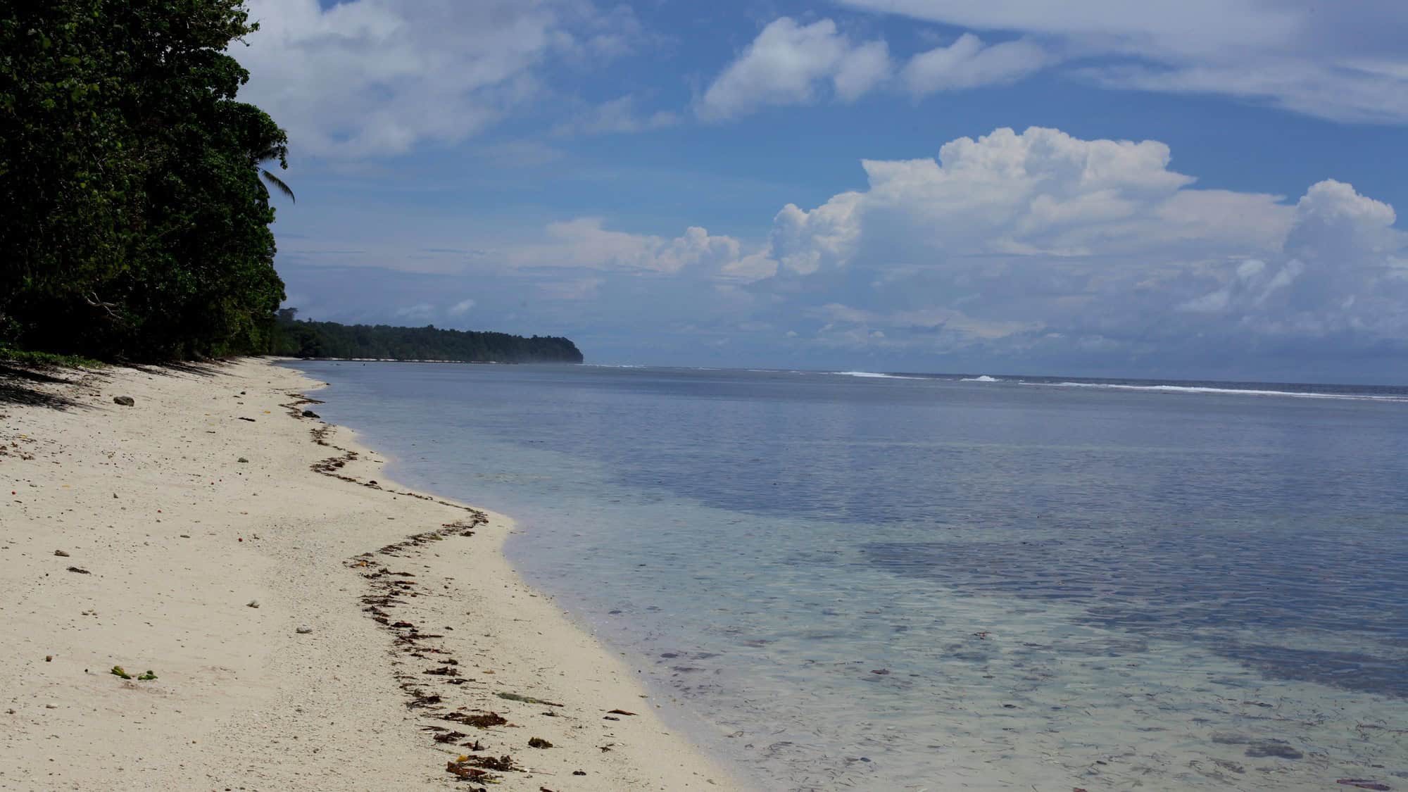 A quiet beach and reef flat on Buka Island in Bougainville under high cloud.