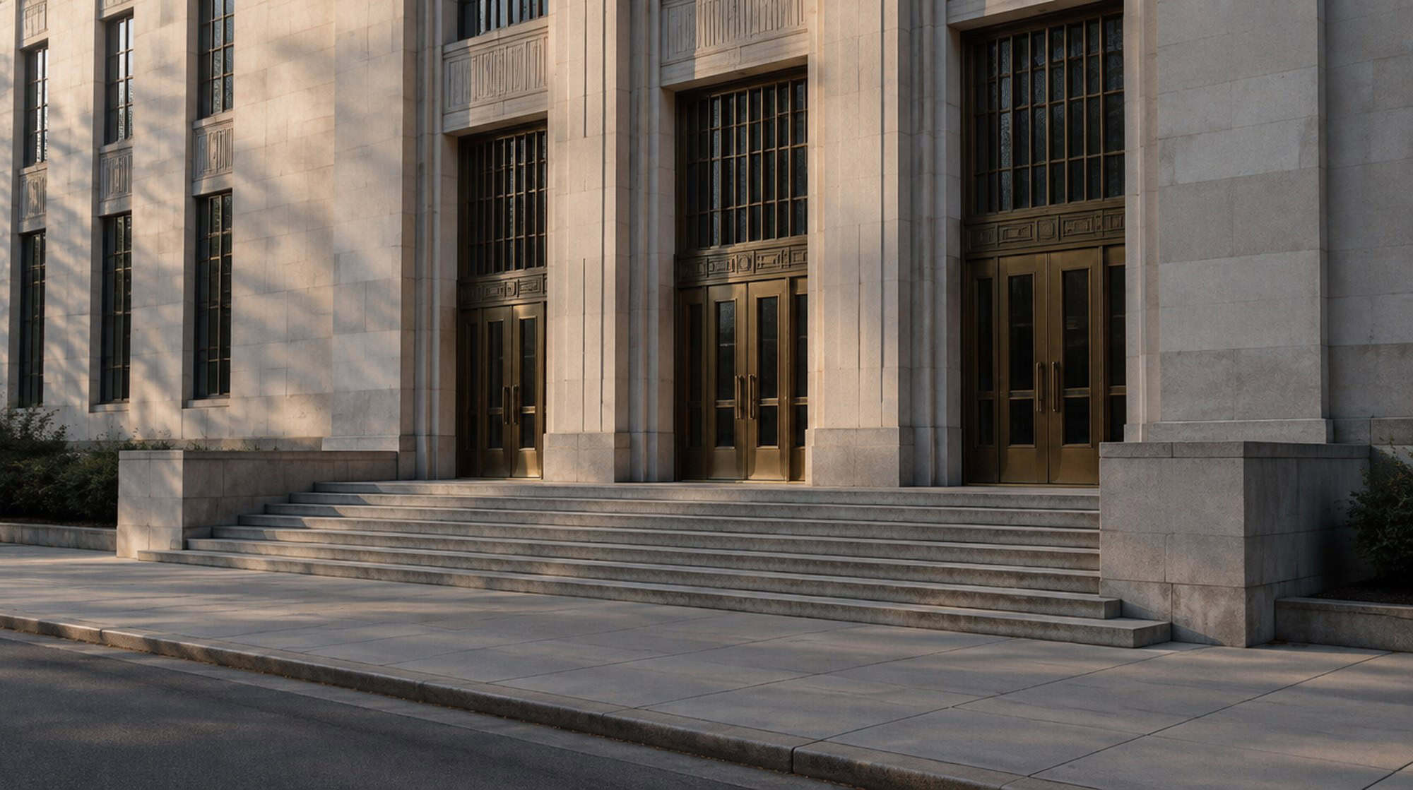 A federal appellate courthouse facade in late afternoon light, limestone columns and tall bronze doors.
