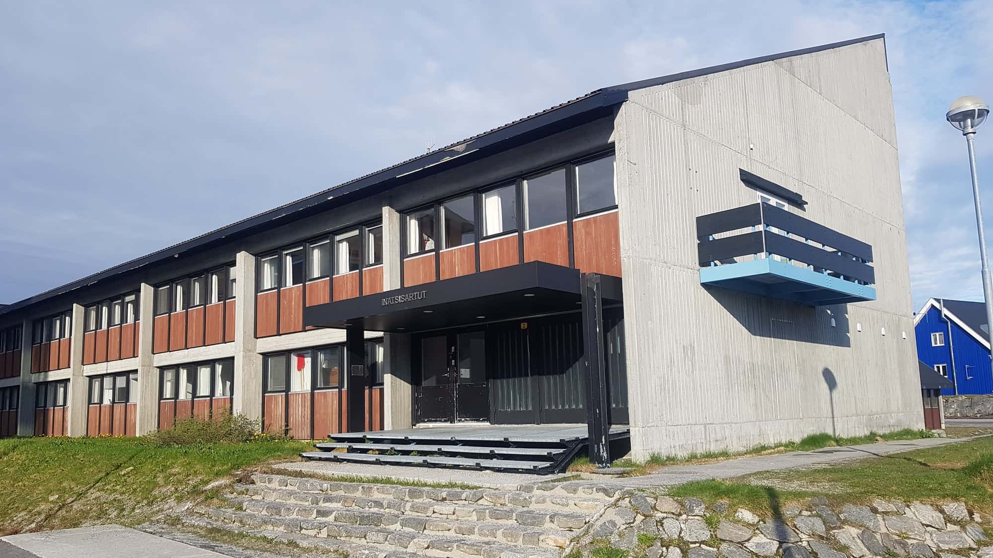 The Inatsisartut building in Nuuk, Greenland's parliament, under a clear sky.